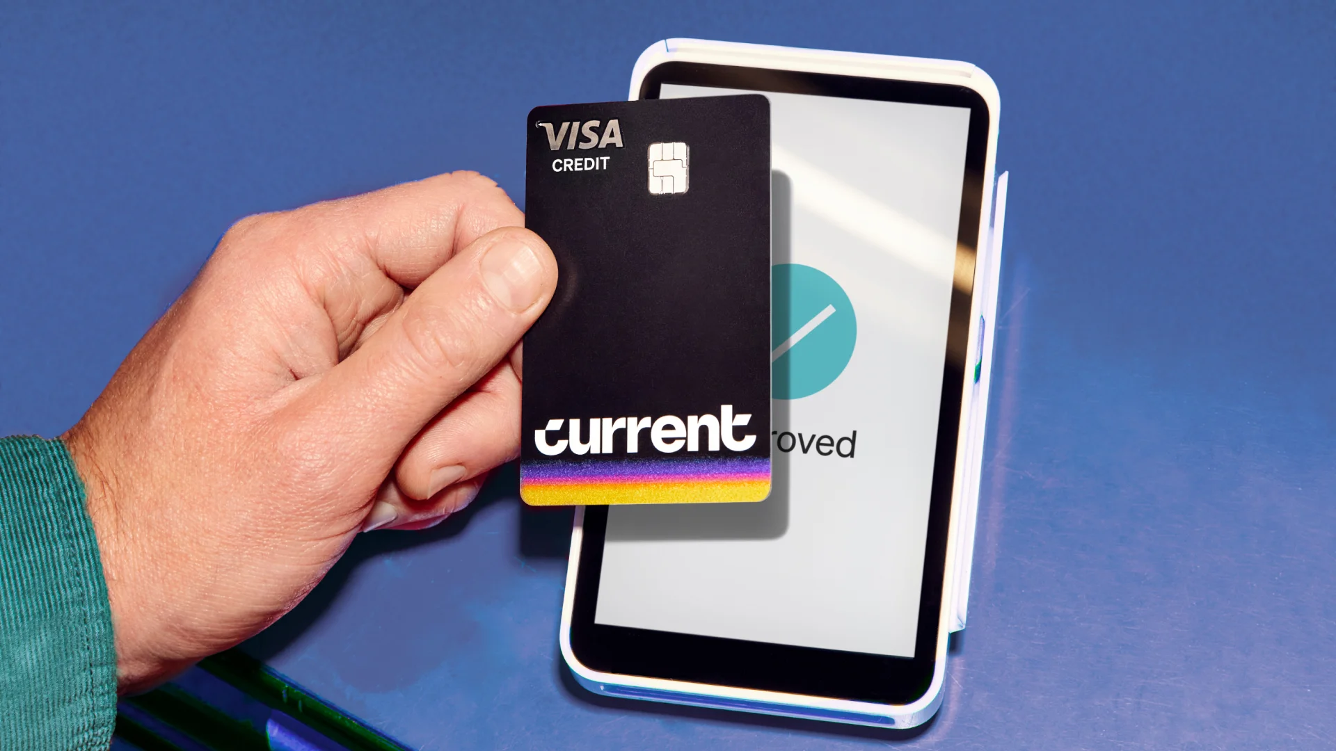 Hand holding Current Visa credit card in front of phone